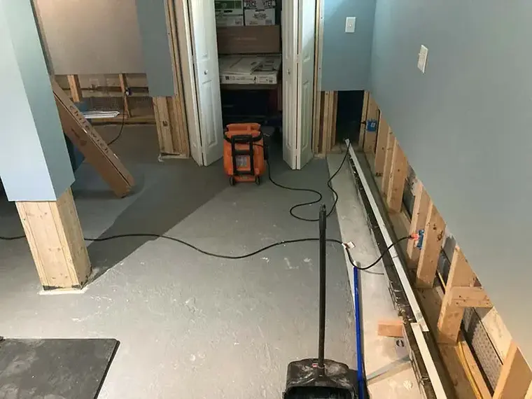 Opened basement walls with a dehumidifier running during a Woodside dry-out
