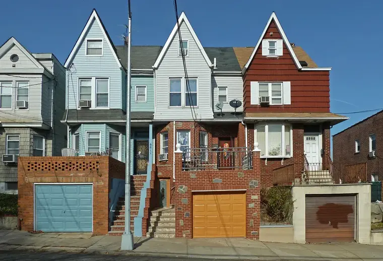 Attached frame and brick houses with garages on a Woodside, Queens street