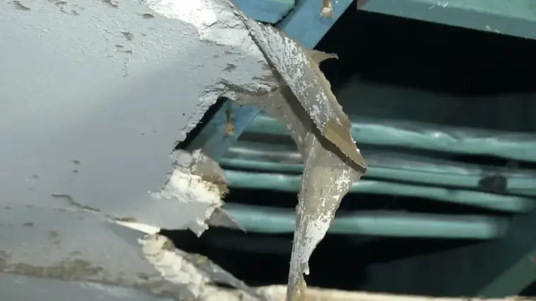Ice-covered pipes exposed behind a broken ceiling after a winter freeze