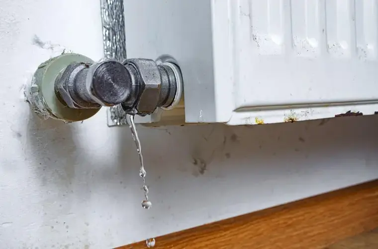 Water dripping from a leaking radiator valve onto a Woodside floor