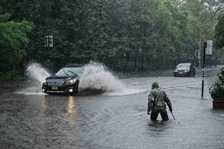 Car splashing through a flooded Queens street during a cloudburst